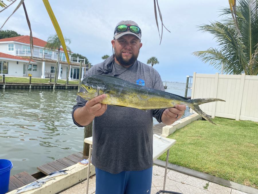 Mark Gabrielli on a dock holding a kingfish