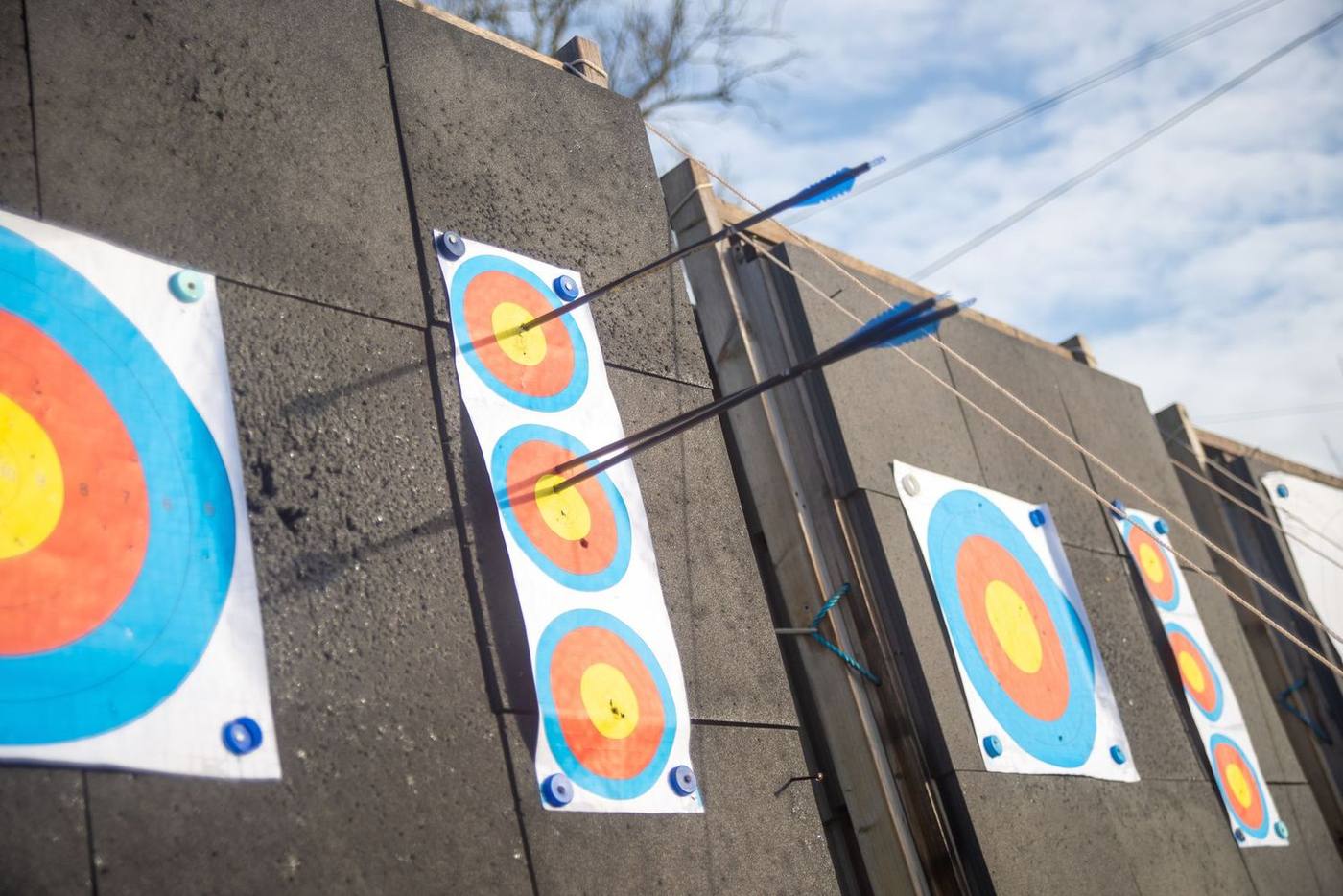 A detailed shot of arrows piercing through colorful archery targets on an outdoor range.
